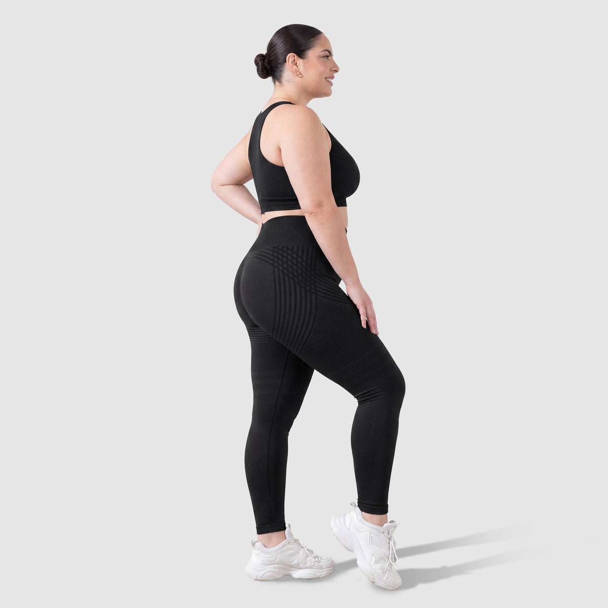 Mujer con leggings anticelulitis Sculpt 3D™ en negro, vista lateral, con las líneas de escultura 3D
