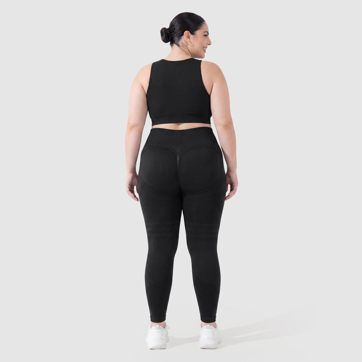 Mujer con leggings anticelulitis Sculpt 3D™ en negro, vista de espalda, glúteos levantados y contorneados