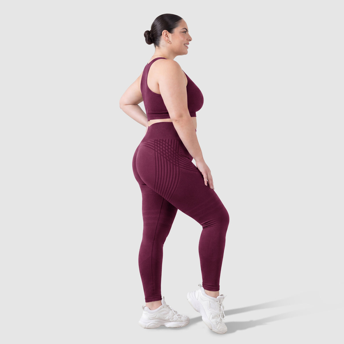 Mujer con leggings anticelulitis Sculpt 3D™ en ciruela, vista lateral, con las líneas de escultura 3D