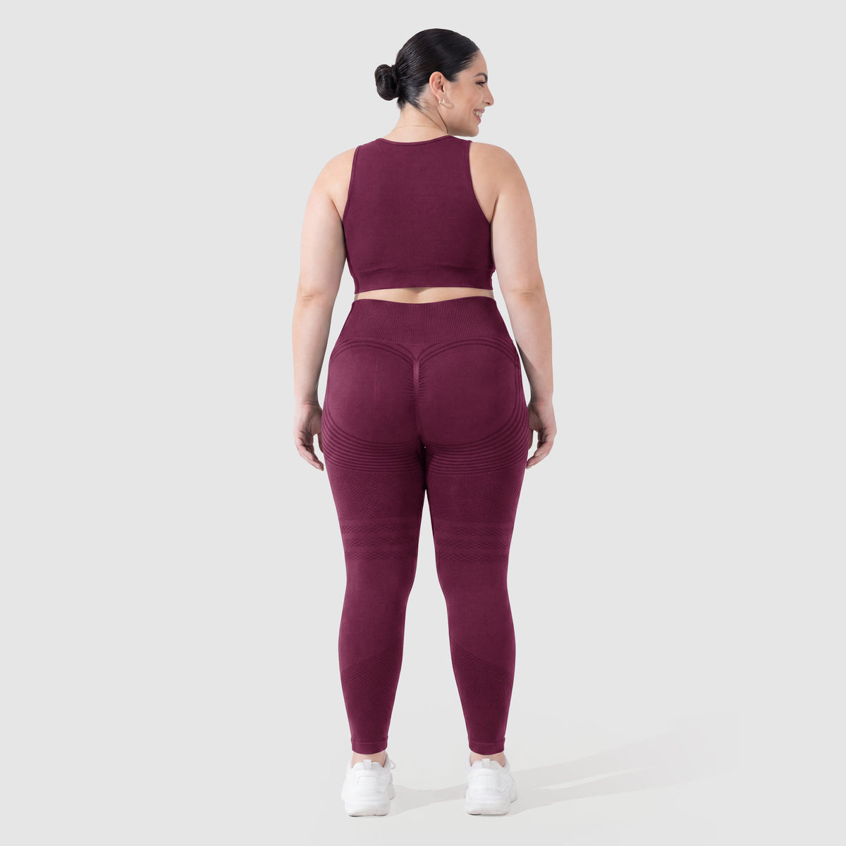 Mujer con leggings anticelulitis Sculpt 3D™ en ciruela, vista de espalda, glúteos levantados y contorneados